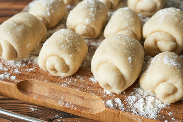 Raw flour buns on a cutting board, close-up view.