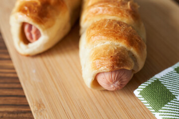 A sausage wrapped in puff pastry on a wooden board, selective focus
