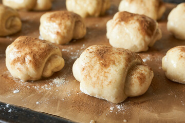 Raw cinnamon rolls on a baking sheet, close-up.