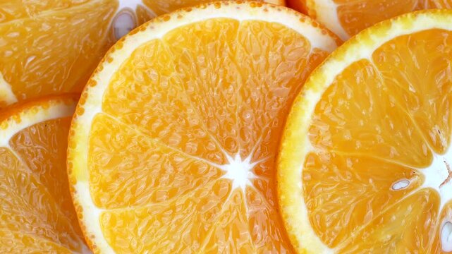 Close up video of mandarin slices surrounded by water ripples. White background with half oranges placed on water waves.
