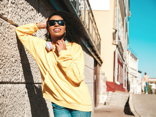 Beautiful black woman with afro curls hairstyle.Smiling hipster model in yellow hoodie. Sexy...