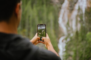 Young man photographing a waterfall in Canmore, Alberta