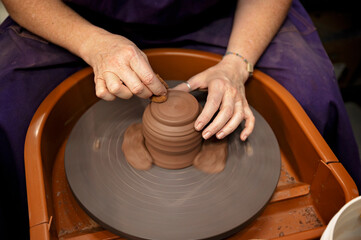 Potter smoothing a spinning clay piece with a sponge on the wheel