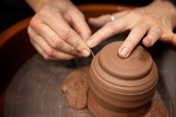 Potter carefully carving fine details into a spinning clay piece