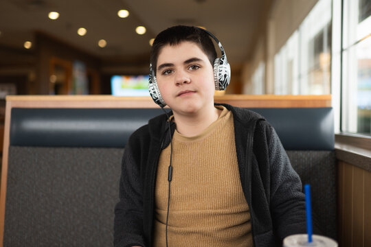 Teen boy with head phones on sits in booth at restaurant