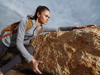 Determined female hiker in activewear overcoming rocky terrain, showcasing resilience and strength...