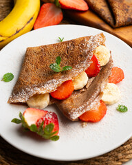 Chocolate crepes with fruit, strawberries and bananas.