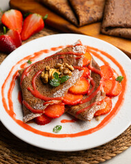 Chocolate crepes with fruit, strawberries and bananas.