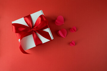 White gift box with red bow on red background