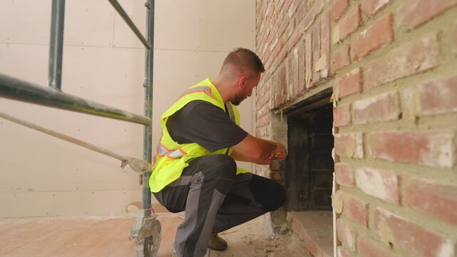 Caucasian male worker measuring fireplace of the wall with measure tool. Builder measure apartment renovation lively house renovation project that showcases teamwork and creativity