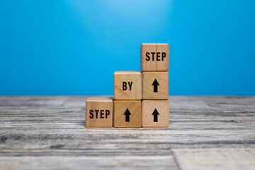 step by step word on wooden blocks staircase isolated on blue background. concept of success...