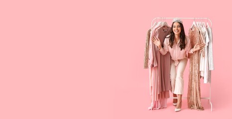 Beautiful young girl near rack with clothes for high school prom on pink background with space for text © Pixel-Shot