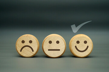 Customer Satisfaction Concept - Wooden Faces Showing Sad, Neutral, and Happy Expressions with a Check Mark