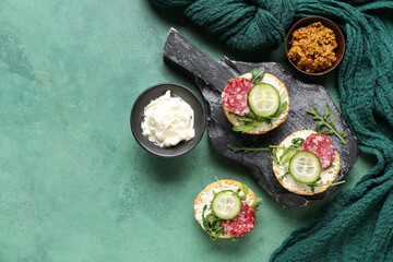 Board with tasty sandwiches, mustard and cream cheese on color background