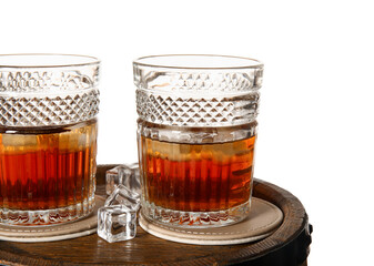 Glasses of cold rum on wooden barrel against white background