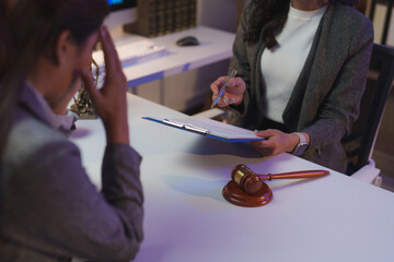 Female lawyer holding a contract while explaining important details to a client in a professional...