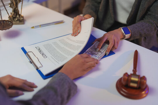 Businesswoman passing cash under a contract to a corrupt official during a meeting, with a judge's gavel and scales of justice highlighting bribery and corruption