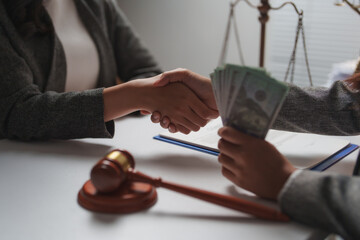 Two lawyers shaking hands in a courtroom, exchanging bribe money, with a gavel and scales of...