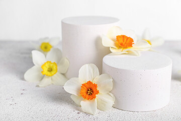 Decorative plaster podiums with flowers on grunge table against white background