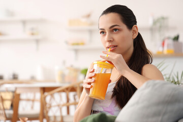 Sporty young woman drinking vegetable juice in kitchen