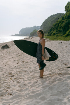 Young woman walking on beach after surfing