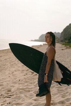 A young woman on the beach with her surfboard