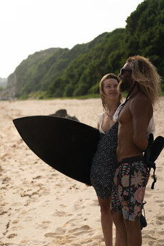 Friends with surfboard standing at beach