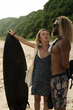 Friends with surfboard standing at beach