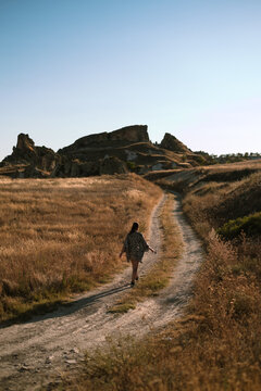 Woman Walks Through Golden Fields and Rocky Terrain in Cappadocia