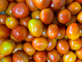 A pile of fresh tomatoes with vibrant red and orange hues. Which is glistening under the sunlight at the traditional market.