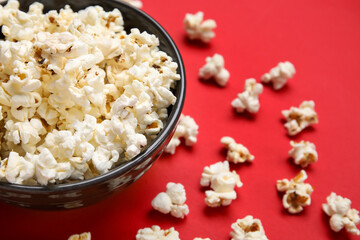 Bowl with tasty popcorn on red background