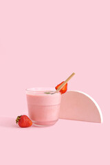 Glass of tasty strawberry smoothie on pink background
