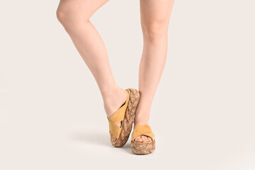 Female legs in flip-flops on white background
