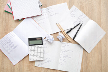 Obraz premium Open copybooks with math formulas and stationery on wooden table