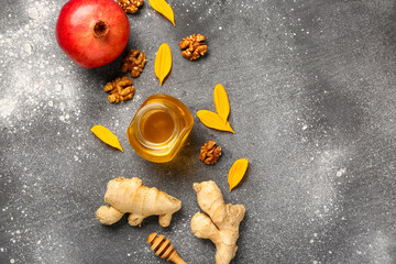 Jar of sweet honey, walnut, ginger and pomegranate on grey background