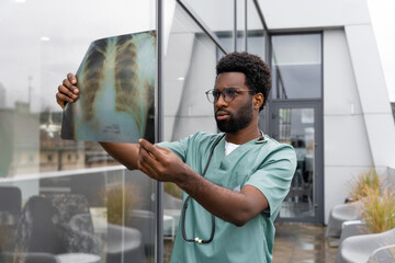 Man doctor looking at x ray picture of sick patient in hospital office