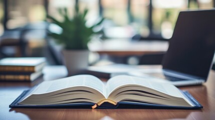 Obraz premium Open Book on Wooden Table in Cafe, Laptop and Plant Blurred Background