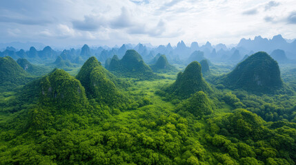 Obraz premium Aerial view of lush green mountains and valleys under cloudy sky