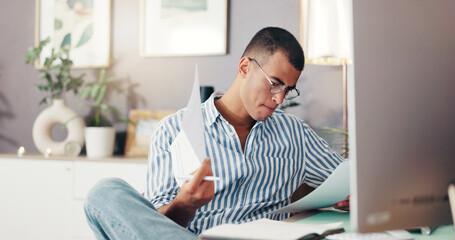 Naklejka premium Man, documents and computer in home with finance, planning and review debt for bills, budget or payment. Person, paperwork and check statement for balance, investment or saving with tax compliance