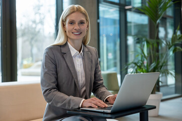 Blonde business woman sitting with a laptop and working