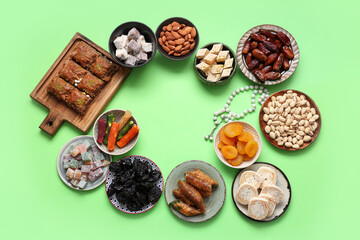 Frame made of different Eastern sweets and tasbih for Ramadan on green background