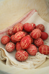 Red Easter eggs with traditional handwritten Hungarian motifs in a wood bowl
