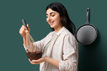 Pretty young woman with whisk and bowl in modern kitchen