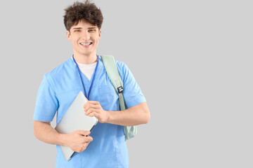 Male medical intern with laptop on light background