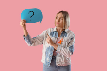 Thoughtful mature woman with ribbon pointing at speech bubble on pink background. Multiple...