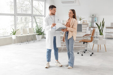 Fototapeta premium Male receptionist with clipboard and patient in clinic