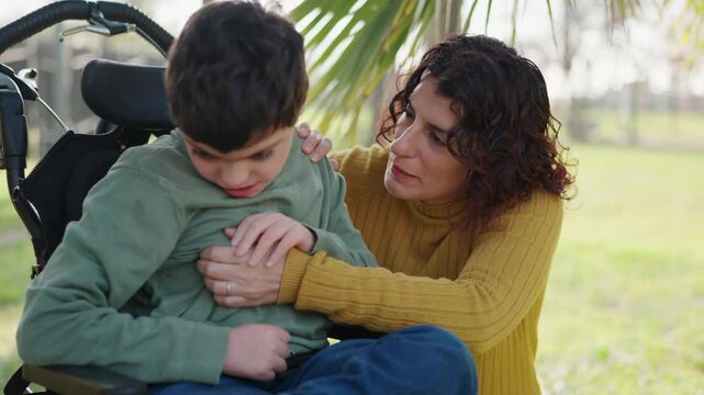 Mother comforting her disabled son sitting in a wheelchair