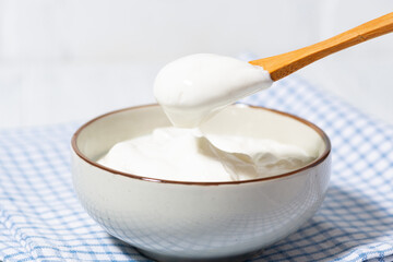 thick greek yogurt in a bowl and a spoon with yogurt