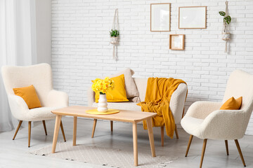 Interior of living room with comfortable sofa, armchairs and vase of flowers on coffee table