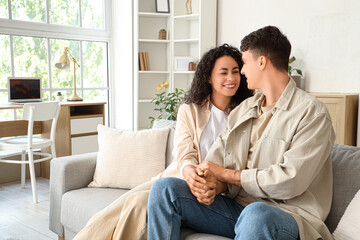Young couple in love holding hands on sofa at home